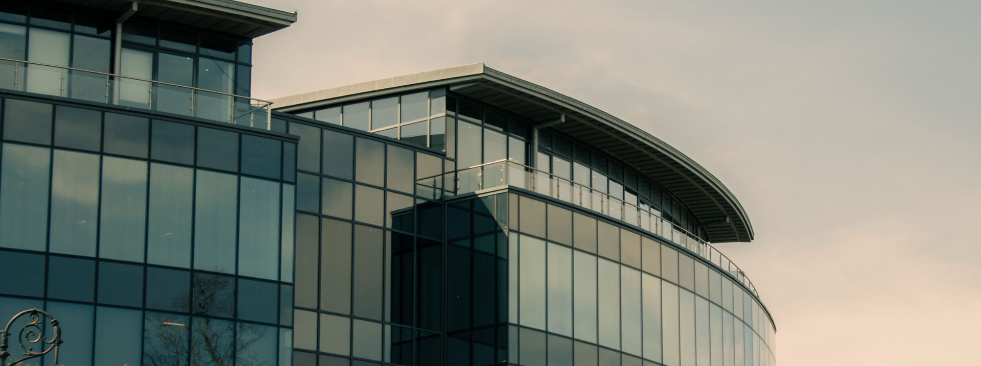 Curved modern office building with reflective glass facade at dusk