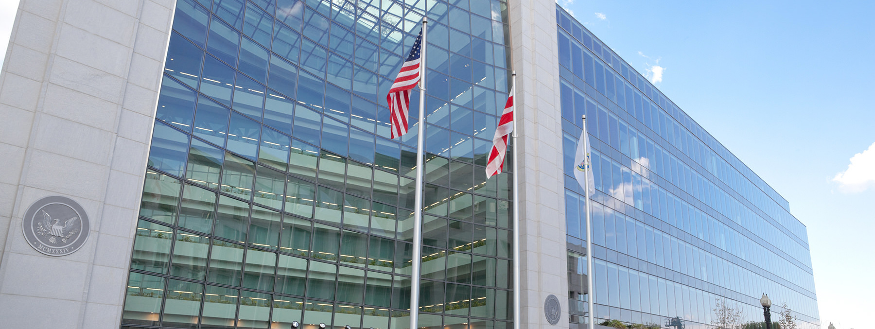 Federal government building with expansive reflective glass facade and American flags